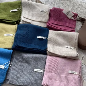 Vista detallada de bufandas de lana 100% pura en varios colores con etiquetas hechas a mano