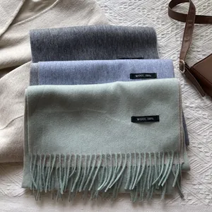Detail view of 100% wool scarves showing fringe edges and black composition labels