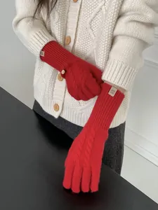 Close-up of bright red cable knit wool gloves featuring intricate retro woven textures