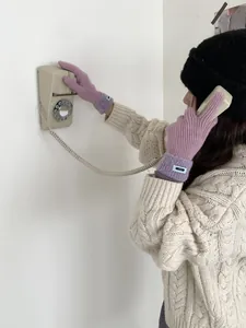 Nahaufnahme von lila gerippten Strickhandschuhen mit blauen Etiketten im Winter