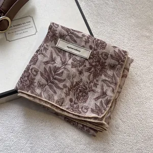 Detail of floral linen scarf featuring explore infinity label on plush background