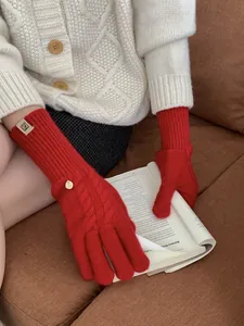 Detailed cable knit texture of red wool blend gloves with logo tags and metal pendant
