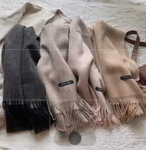 Detail of 100% wool scarves in neutral colors with fringe and material labels