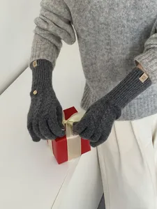 Detail showing charcoal grey wool knit gloves with premium leather logo patch and metal stud