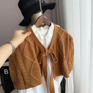 Close-up of caramel knit shawl featuring intricate cable and diamond patterns with tie-up
