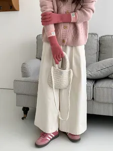 Detail shot of pink knitted touchscreen gloves paired with a cozy cardigan and woven bag