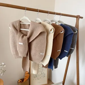 Knitted waffle textured shawls in khaki, white and grey on wooden hangers