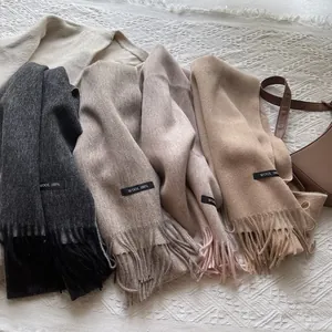 Detail of 100% wool scarves with fringe in grey, beige, pink and camel colors