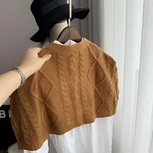 Close-up of caramel cable knit vest showing detailed texture and ribbing over white shirt