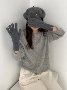 Detailed texture of grey wool knit gloves with ribbed cuffs and small metal logo