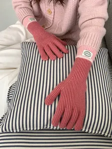 Detailed texture of pink ribbed knit touchscreen gloves with a soft woven logo patch