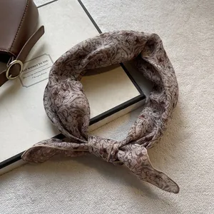 Dettaglio di un foulard di seta con nodo che mostra la trama morbida e il motivo floreale vintage