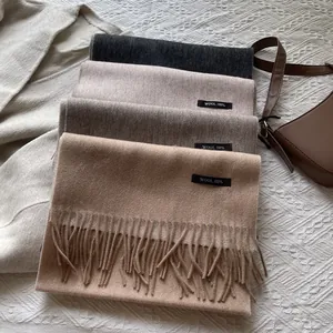 Detailed stack of 100% wool fringed scarves in grey, beige, taupe and camel colors