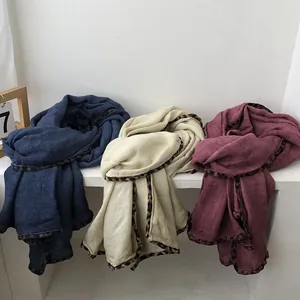 Detail view of navy, cream and burgundy knitted scarves with leopard print trim edges