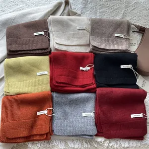 Detalle de bufandas de lana 100% pura en varios colores con flecos y etiquetas