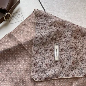 Dettaglio ravvicinato della texture del foulard in seta kaki con etichetta in tessuto