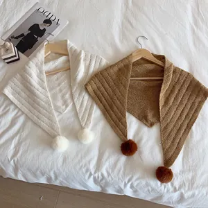 Knitted triangle shawl scarves with pom-poms in cream and brown on wooden hangers