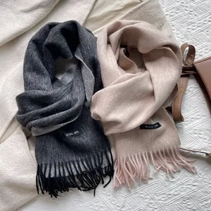 Detail of 100% wool woven scarf with delicate fringe edges and material care label