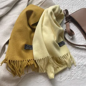 Detail of wool scarves in ginger and off-white with long tassels and fabric label