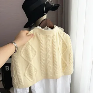 Detail of cable knit patterns and diamond textures on cream white wool shawl shrug