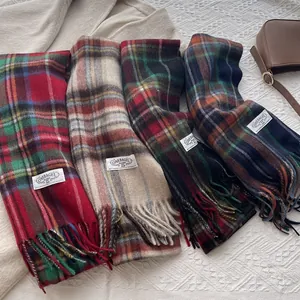 Classic plaid wool scarf with tassels in multiple warm autumn colors on a soft bed