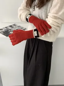 Detail of red knit touchscreen gloves with black cuff and white label on the wrist
