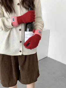 Detailansicht der roten Strickhandschuhe mit rosa Plüschbündchen und schickem Blauen-Label