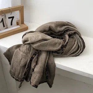 Detail of soft cotton linen scarf featuring leopard print edges and warm brown texture