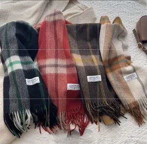 Flat lay of plaid cashmere scarves in green, brown, and ginger with tassels and brand labels
