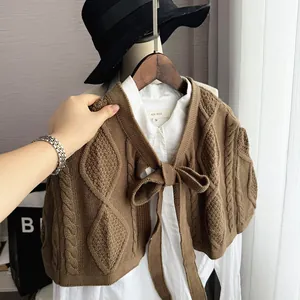 Close-up of brown knit shawl featuring diamond texture and ribbon bow tie detail