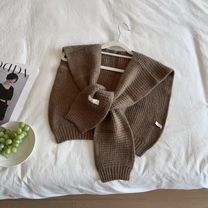 Close-up of dark brown knitted shawl showing textured waffle knit pattern and cozy fabric