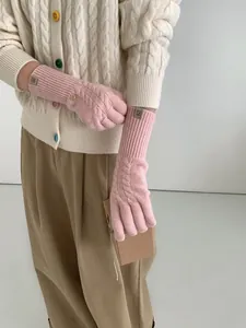 Detail of pink wool knit gloves with cable pattern and brown leather patch on the wrist