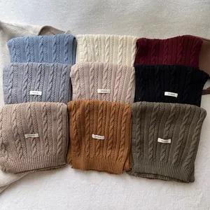 Classic cable-knit 100% wool scarves in nine elegant colors neatly arranged on a rug