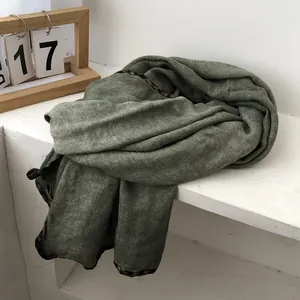 Detailed view of moss green shawl featuring animal print borders and soft knit texture