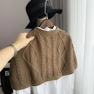 Detailed knit texture of brown shawl featuring classic cable and diamond patterns