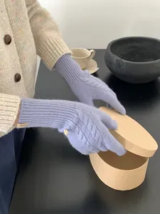 Detail of lavender wool knit gloves with cable pattern, leather logo, and button cuff