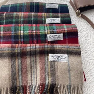 Stacked collection of plaid wool scarves with tassels in various winter color patterns