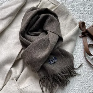 Detail of dark brown wool scarf with tassel fringe and a small woven designer label