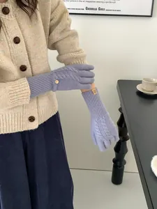 Close-up of light purple cable knit wool gloves featuring long ribbed cuffs and logo detail