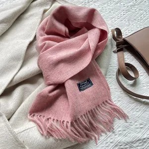 Detail of pink wool tassel scarf with premium stitched brand label and soft texture