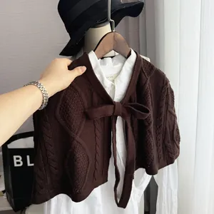 Detail of dark brown knit shawl with a large bow-tie and textured diamond patterns