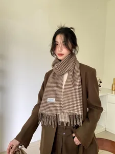 Detail of wool houndstooth scarf showing fringed edges and brand label on brown blazer