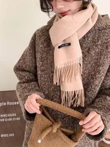 Detail of 100% wool scarf featuring delicate tassel edges and a soft beige texture