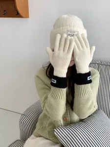 Nahaufnahme von Winter-Accessoires: cremefarbene Strickmütze und Handschuhe mit Kontrast