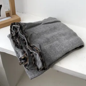 Detail view of grey cotton-linen scarf featuring leopard print edges on a white surface
