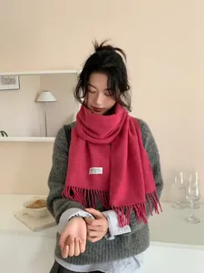 Detail eines rosa Wollschals mit weichen Fransen und einem minimalistischen Markenlabel