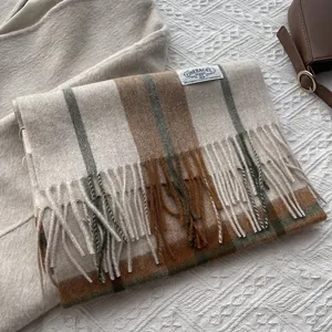 Detail of plaid cashmere scarf with long tassels and minimalist brand label on fabric