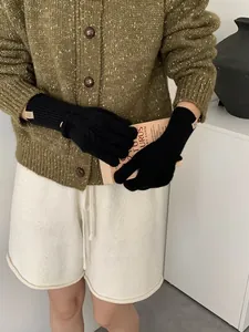 Detail of black knit wool gloves featuring a brown leather label on the wrist cuff