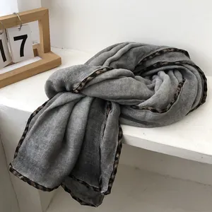 Detail of grey scarf with leopard print borders neatly folded on a minimal white shelf