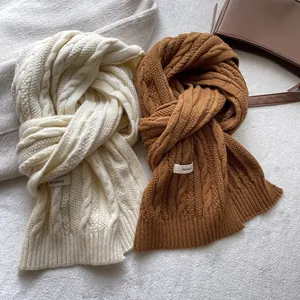 Detailed close-up of chunky cable knit wool scarf in cream and caramel brown colors